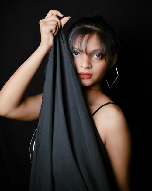 Free Captivating portrait of a woman in a black silk sheet against a black background. Stock Photo