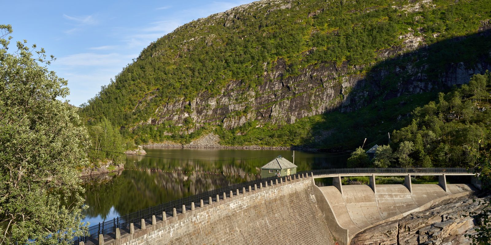A large dam nestled in a mountainous landscape with calm water