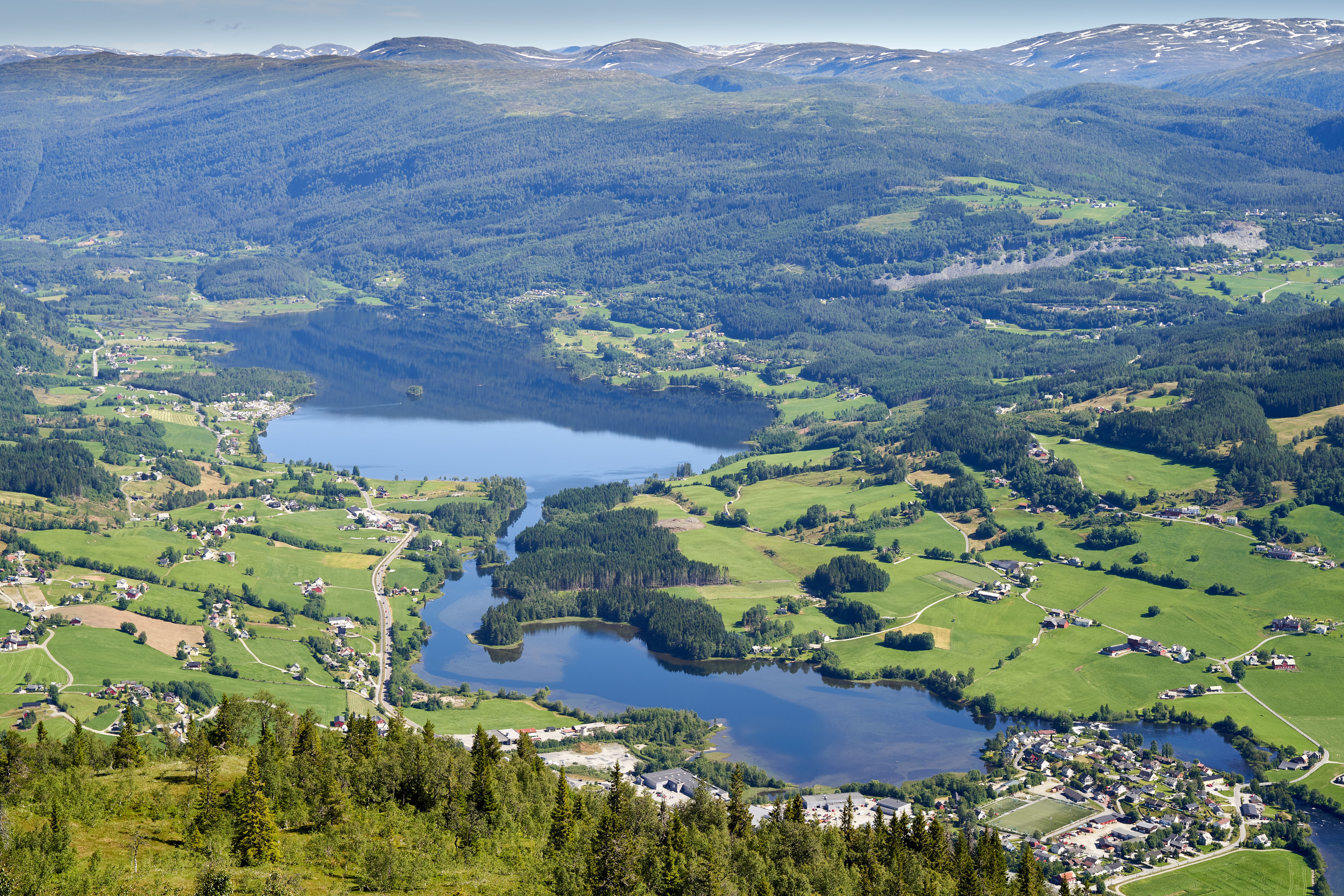 Aerial view of a peaceful countryside with lakes and lush greenery on a sunny day.