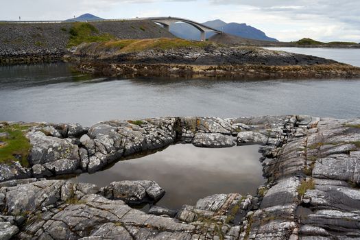 Beautiful coastal view with natural rock formations and a scenic bridge over calm waters.