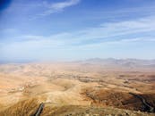 鸟瞰蔚蓝天空下广阔干旱的沙漠景观