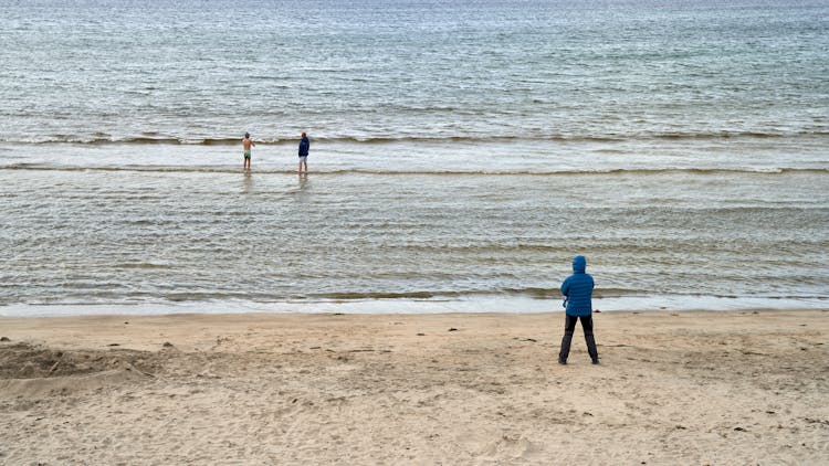 People Enjoying Sea On Cold Day