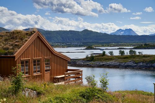 Free Charming wooden cabin by a picturesque lake surrounded by mountains. Stock Photo