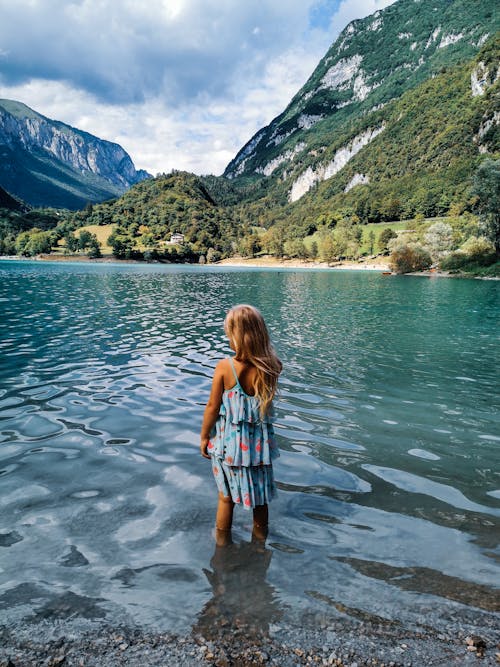 Little Girl in Blue Dress Standing in Body of Water