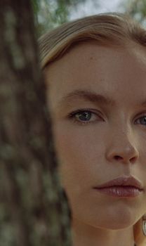Close-up portrait of a woman beside tree, conveying nature's serene beauty.