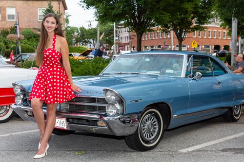 Free Woman in polka dot dress posing with vintage blue car at a classic car show. Stock Photo