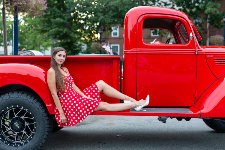Woman In Dress Sitting On Classic Red Truck