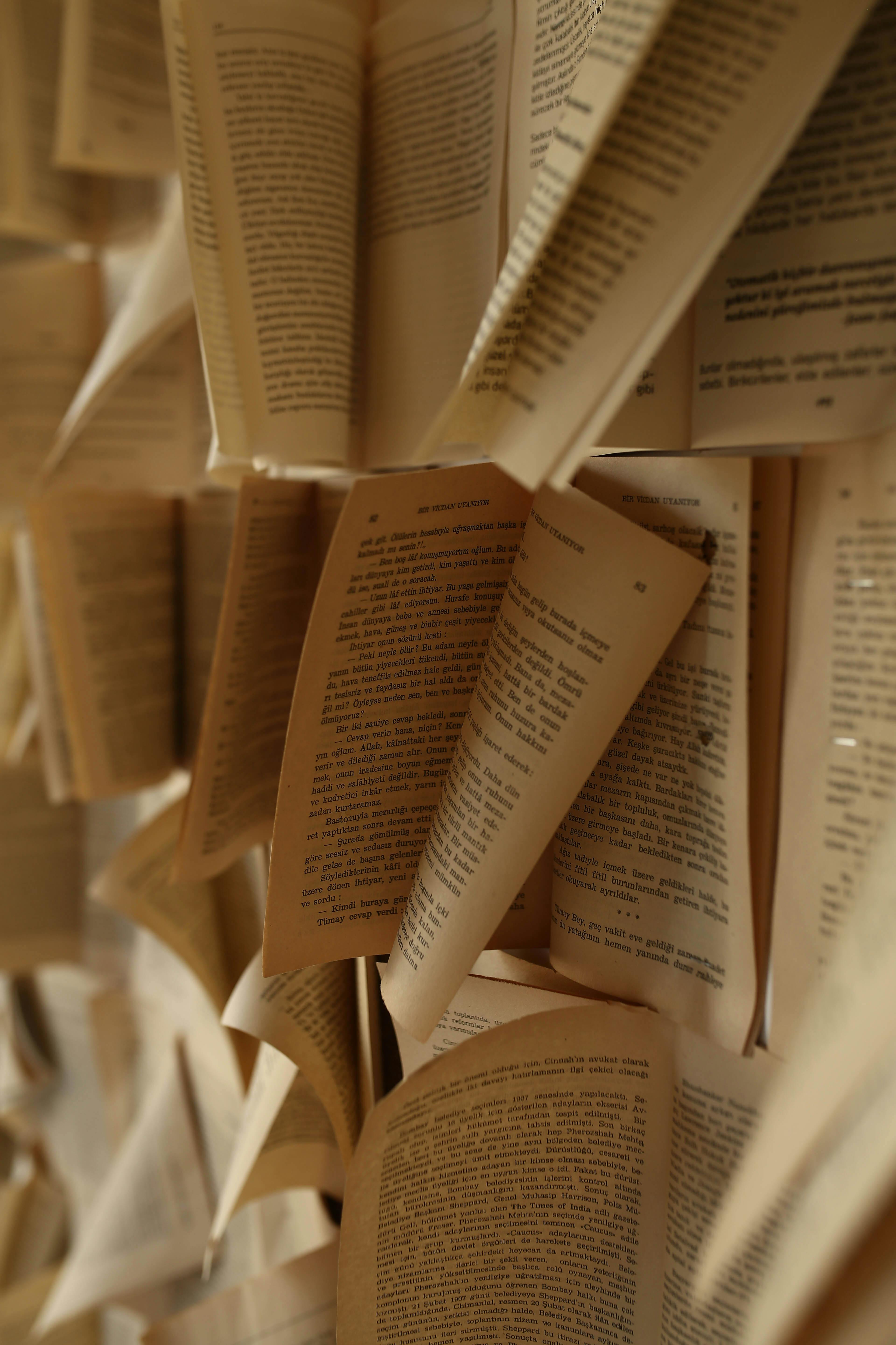 Creative display of open book pages on a wall, featuring selective focus and a vertical perspective.