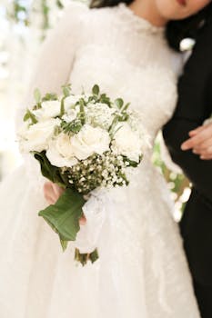 Close-up of a bride holding a beautiful bouquet of white roses and baby's breath on her wedding day.