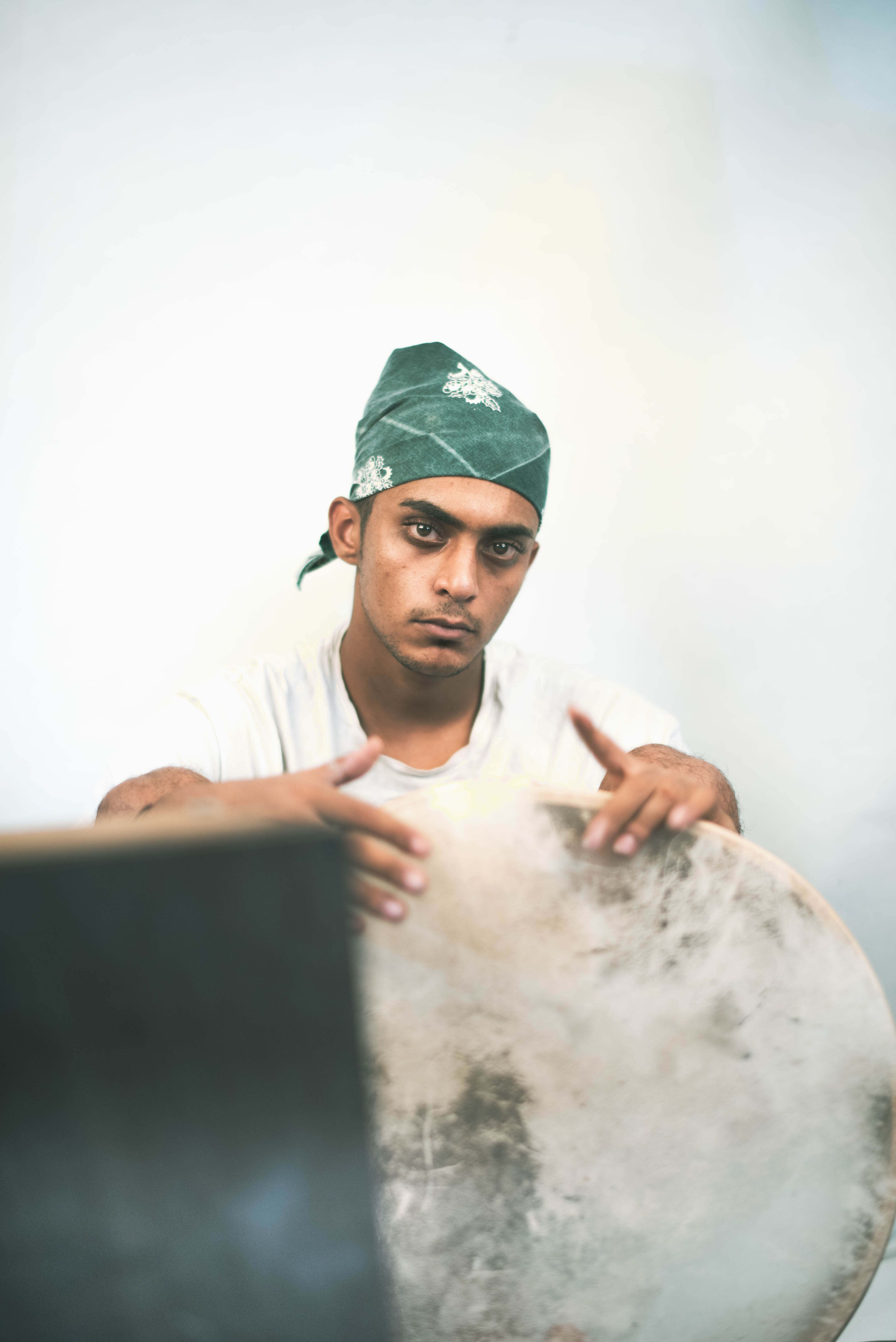Portrait of a serious man with a bandana holding a drum in a studio setting.