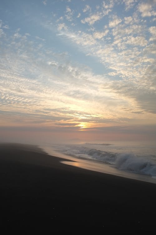 Crashing Waves Under White Clouds and Blue Sky