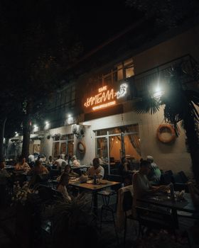 Cozy nighttime atmosphere at an outdoor restaurant in Sochi, Russia with diners enjoying the evening.
