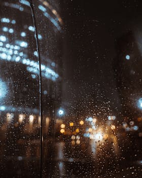 Moody night scene with city lights reflecting on rain-specked windows in Moscow.