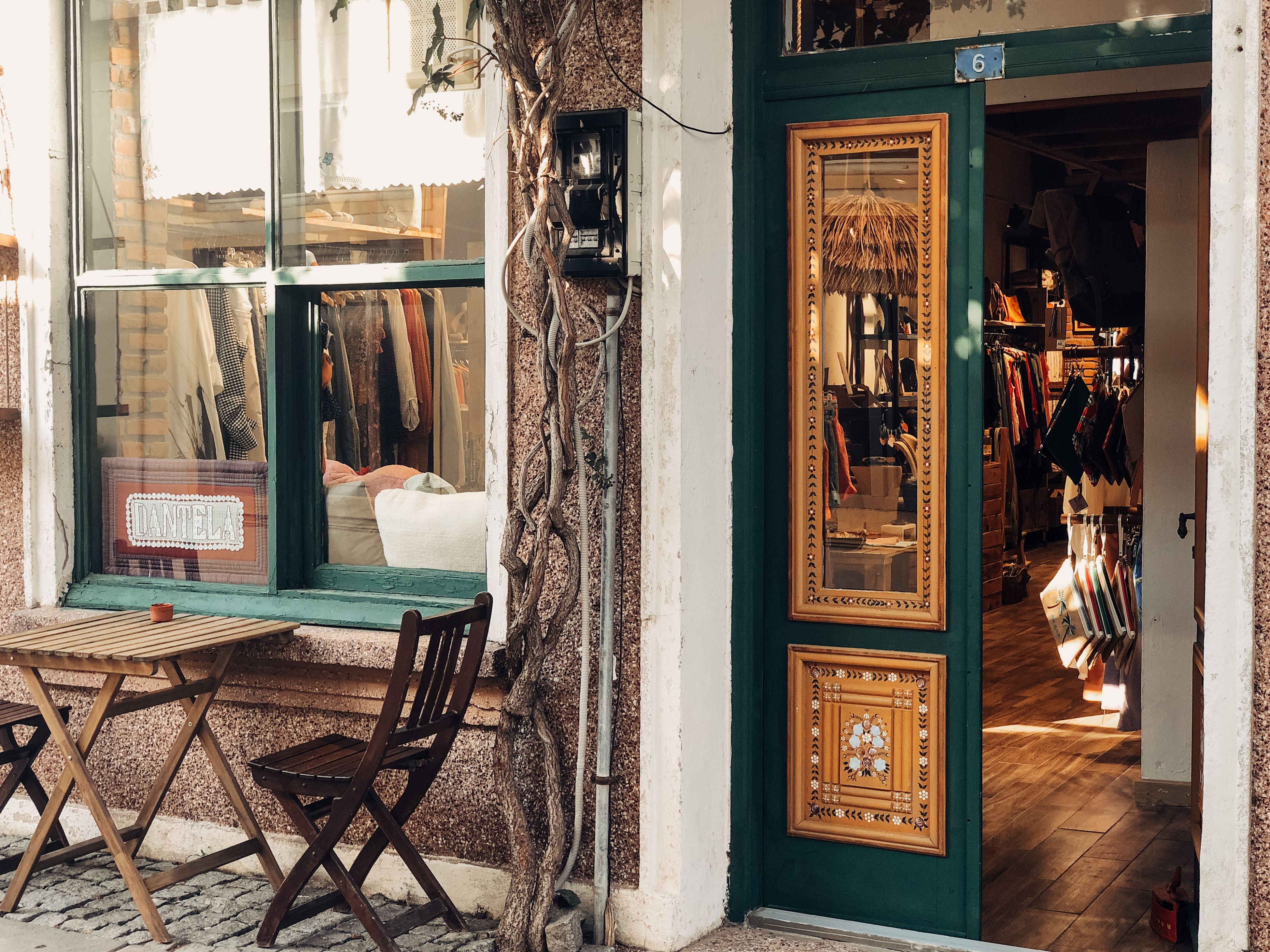 Quaint storefront with green door, ornate gold panels, and small outdoor table and chairs by the window