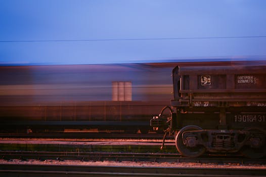 Long exposure shot of a speeding cargo train under a blue sky at twilight.