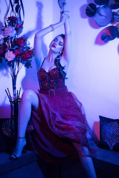 A Woman in a Long Sparkly Dress Posing While Sitting