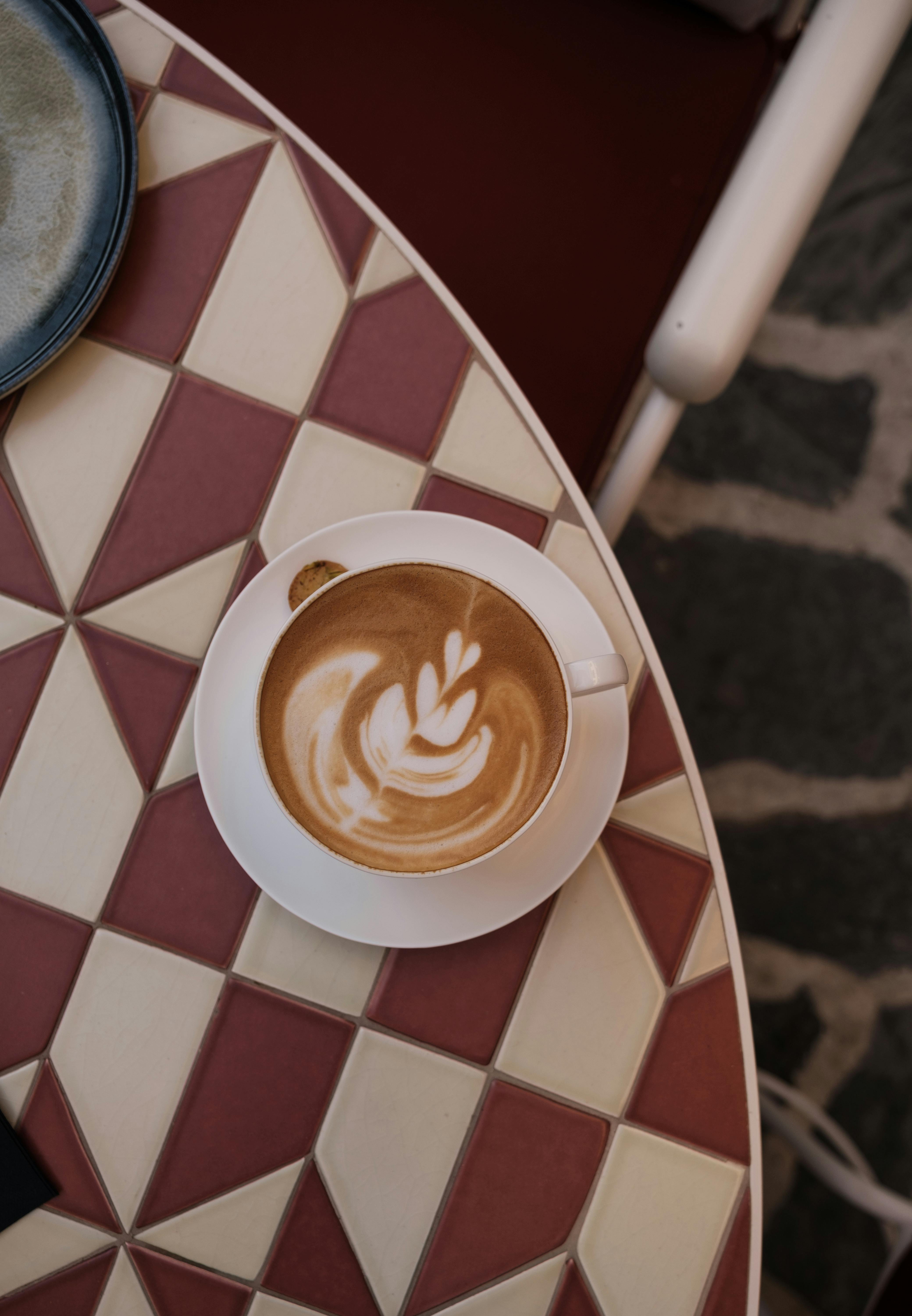Aerial view of a cappuccino with latte art on a geometric patterned table.