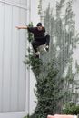 Man in Black T-shirt and Black Pants Jumping on White Wall
