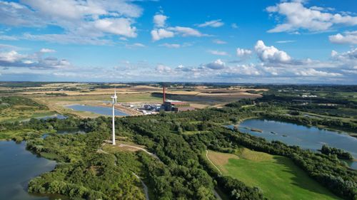 Free A stunning aerial view of a wind turbine amid lush green countryside and lakes in Central Bedfordshire, UK. Stock Photo