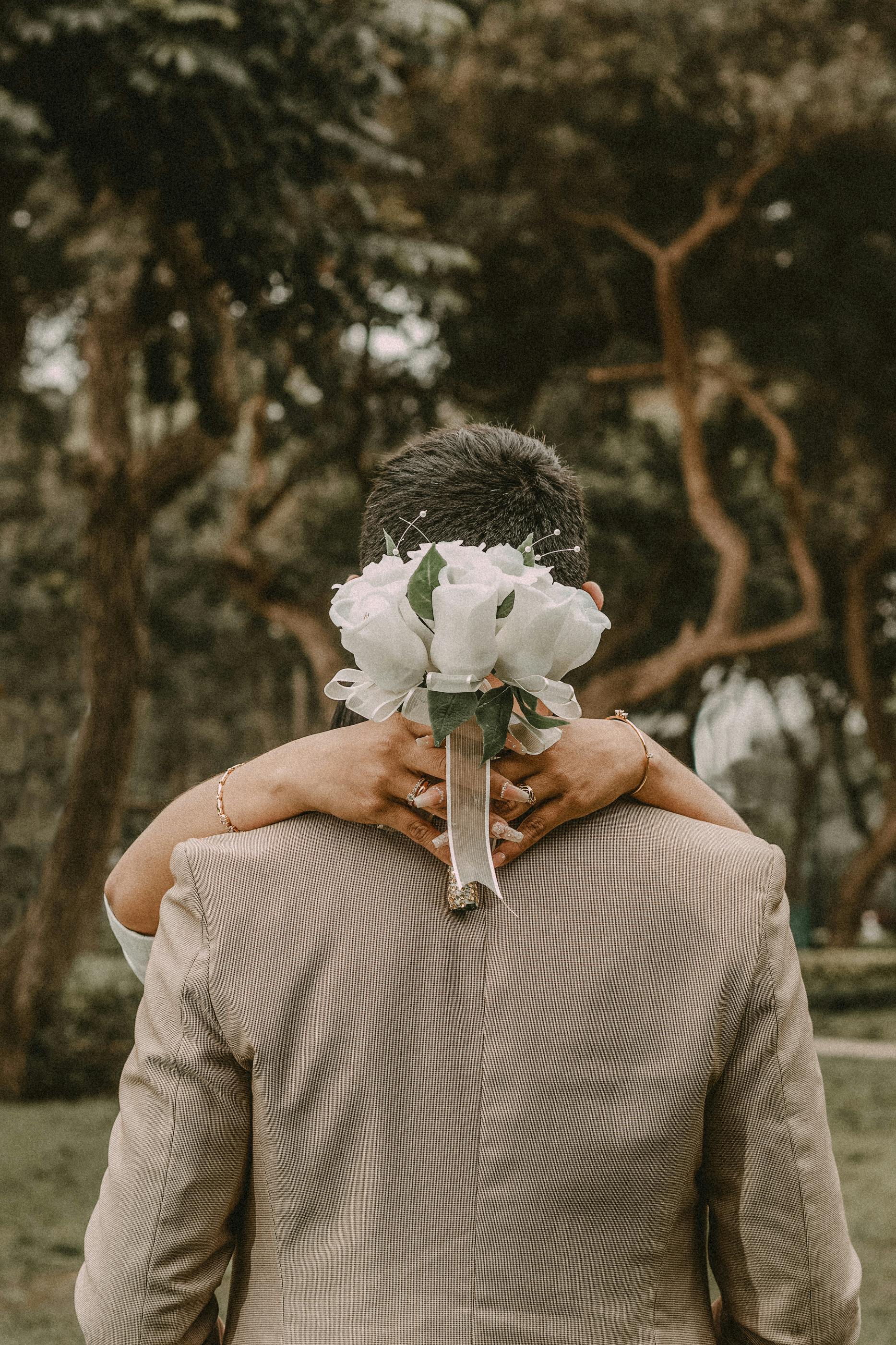 woman holding a white bouquet of flowers while hugging a man