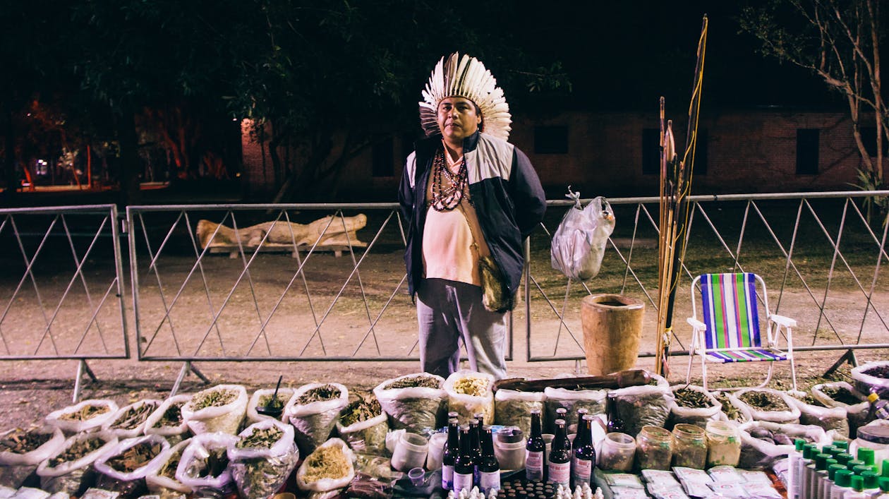 Man Wearing a Traditional Plume Selling Products on a Local Market 