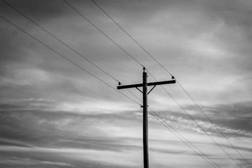 Monochrome Photo of a Utility Pole Under a Cloudy Sky