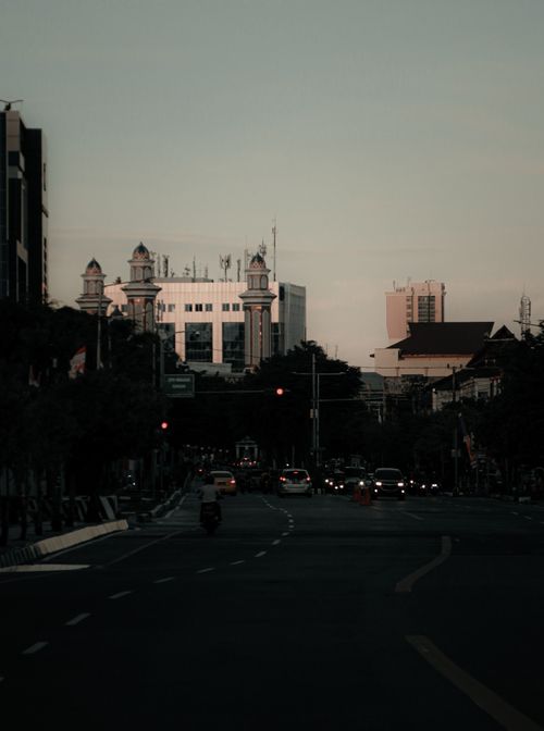 Free A serene evening view of an urban street with cars and beautifully lit buildings. Stock Photo
