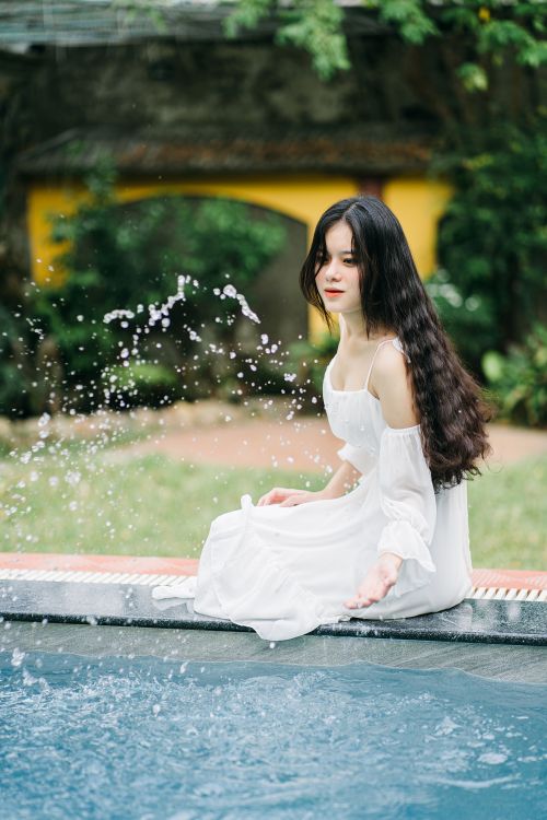 Attractive Asian woman touching water in pool · Free Stock Photo