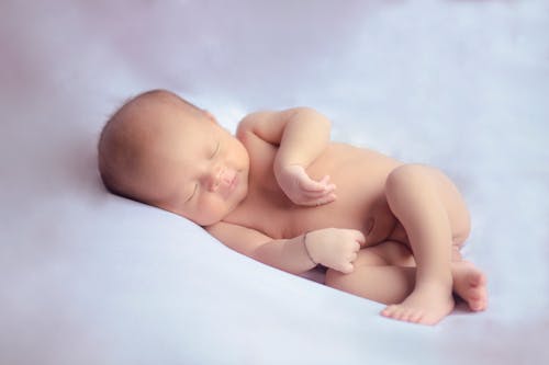 Baby Lying on White Cushy Surface