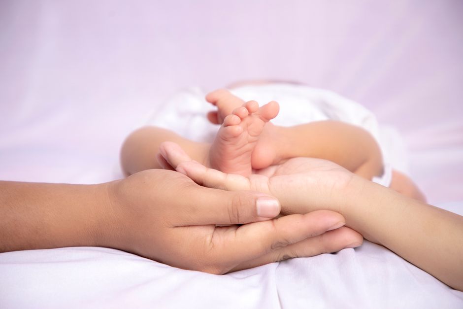 A touching image of a baby's feet cradled by parents' hands, symbolizing care and affection.