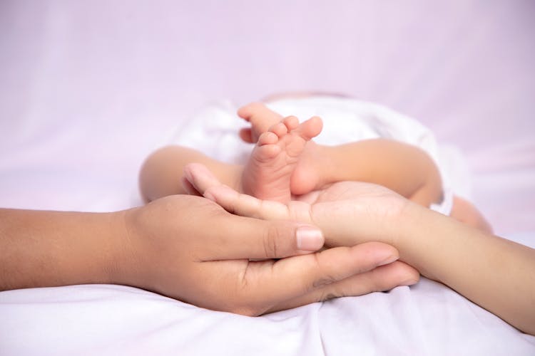 Man And Woman Hands Supporting Baby Feet