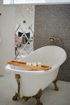Elegant bathroom featuring a freestanding tub, mosaic wall, and decorative candles for a relaxing atmosphere.