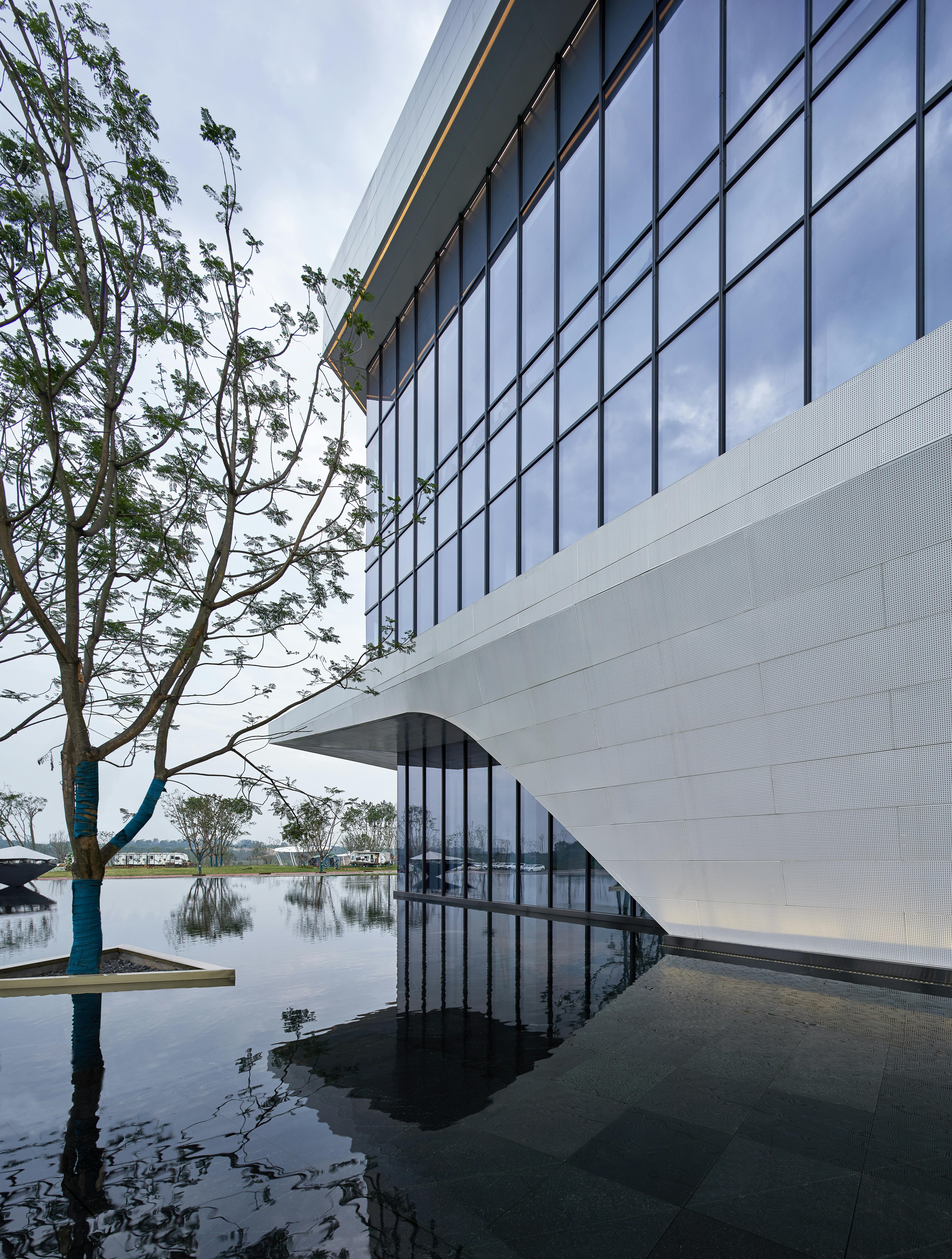 Stunning modern architecture with reflective facade by a tranquil pond in Sichuan, China.