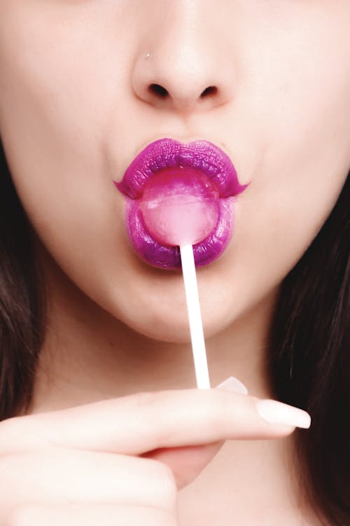 Woman Wearing Purple Lipstick With Pink Lollipop