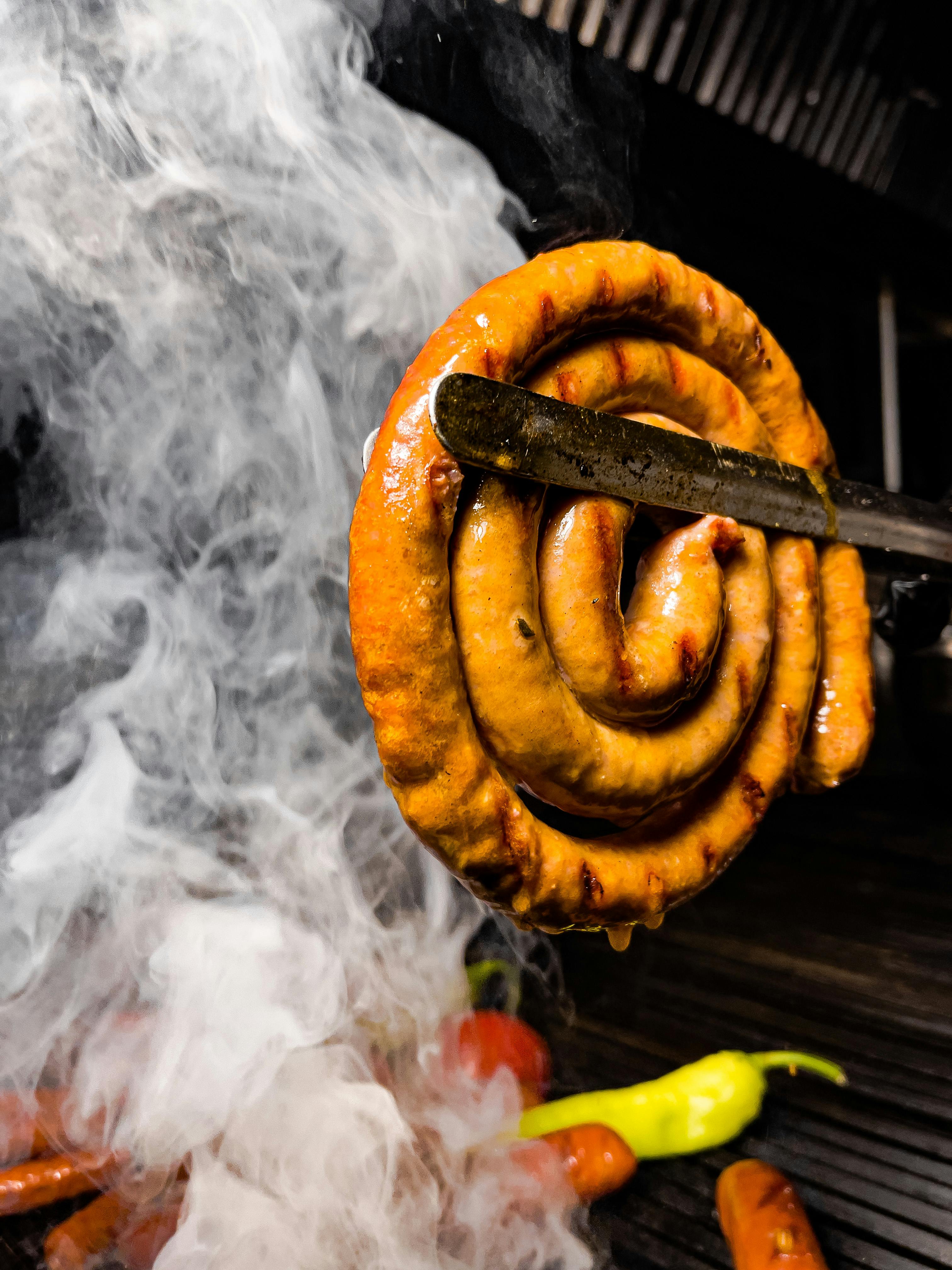 sausage in grill tongs over the grill grid