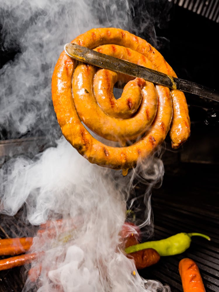 Sausage In Grill Tongs Over The Grill Grid 