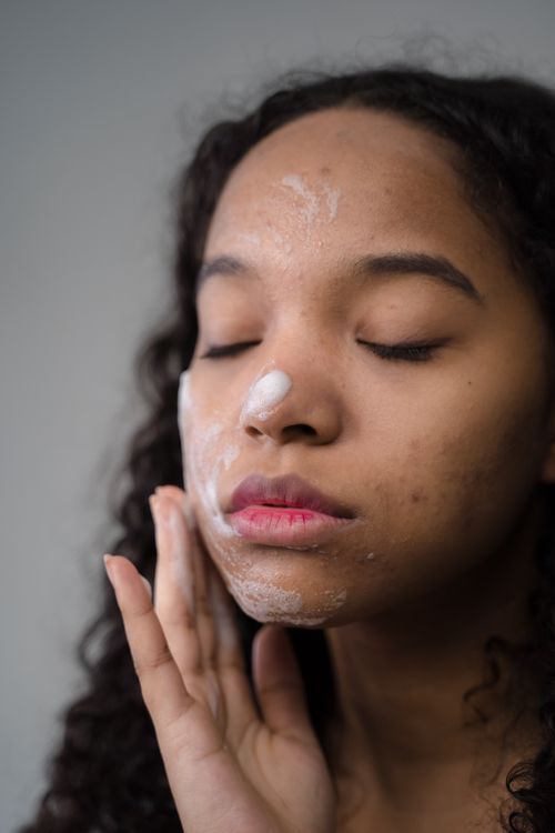 Free Close-up of a young woman applying facial cleanser, focusing on skincare and self-care. Stock Photo