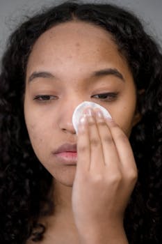 Close-up of a woman using a cotton pad for skincare, focusing on self-care and hygiene.