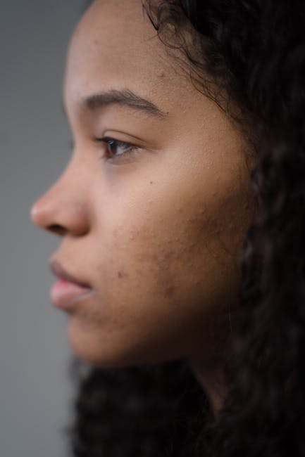 A close-up side profile of a young woman showcasing natural skin texture and curly hair.