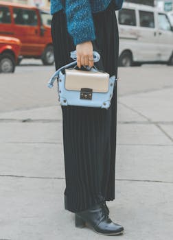 城市街道上，时尚女人提着别致手袋，穿着高筒靴