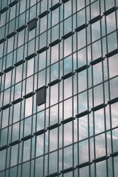 Free Vertical view of a modern skyscraper's glass facade reflecting clouds in Wiesbaden, Germany. Stock Photo