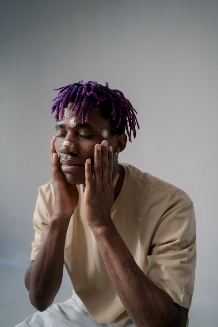 A Man With Purple Hair Touching His Face