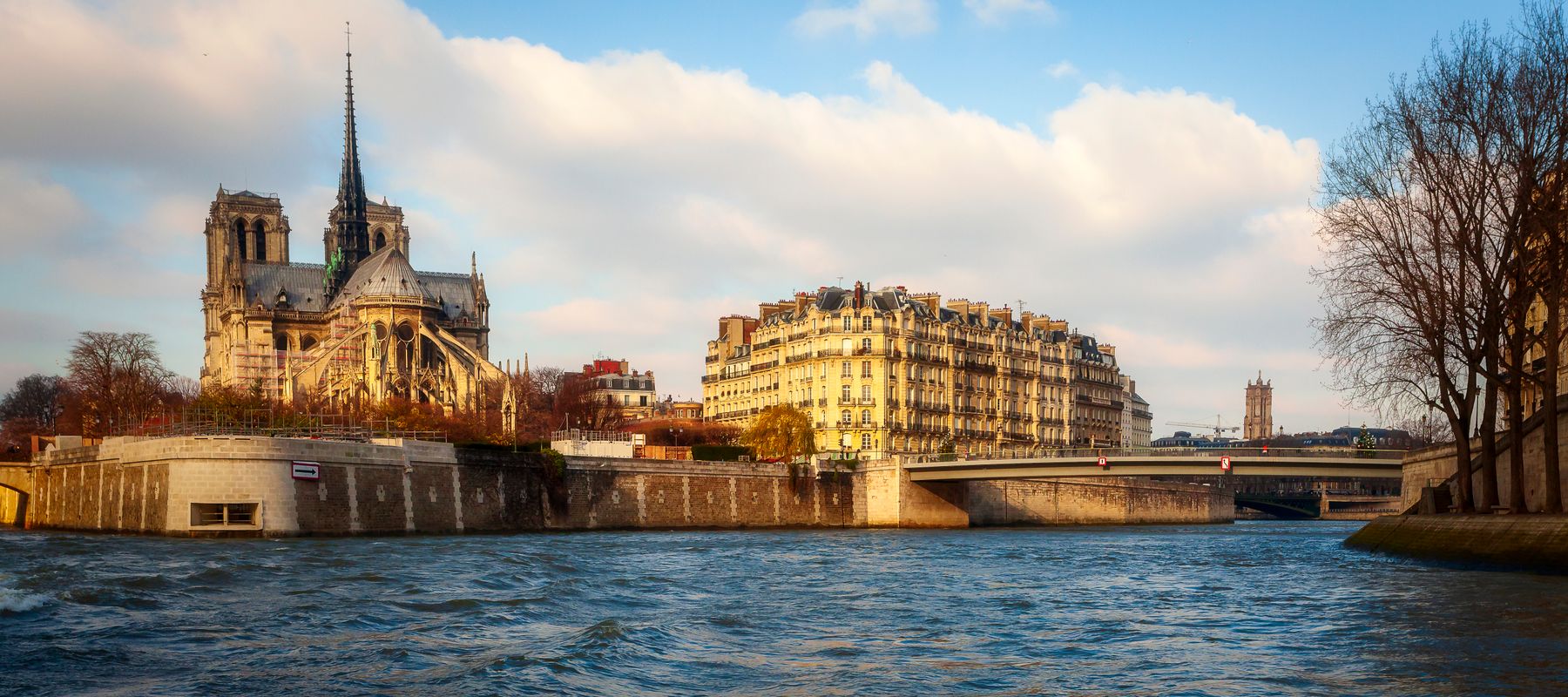 Scenic view of Notre Dame Cathedral by the Seine River in Paris during the day.