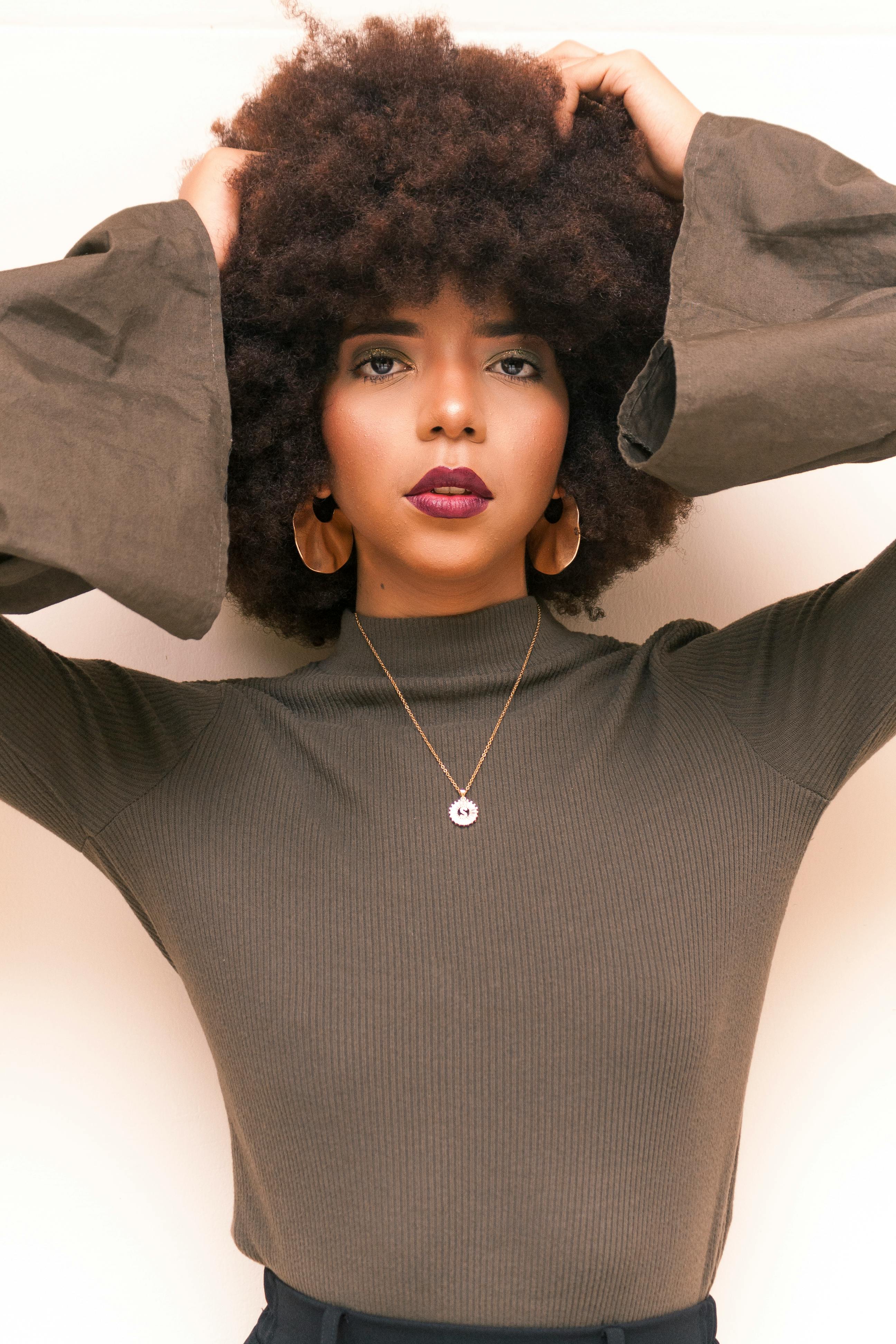 Elegant portrait of a woman with afro hair posing confidently indoors, showcasing modern fashion and individuality.