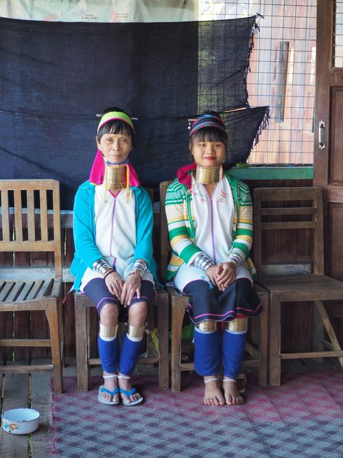 Free Two Kayan women wearing traditional attire with neck rings, sitting indoors. Stock Photo