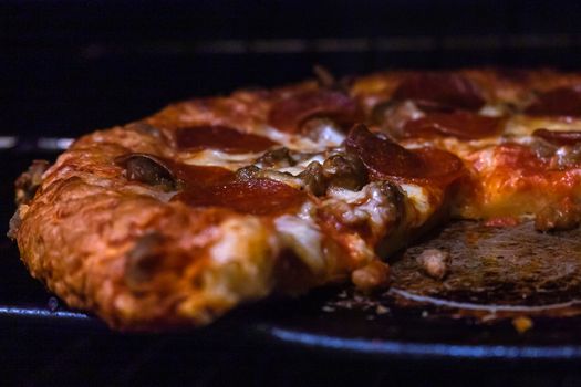 Delicious pepperoni pizza baking in oven with melted cheese and crispy crust.