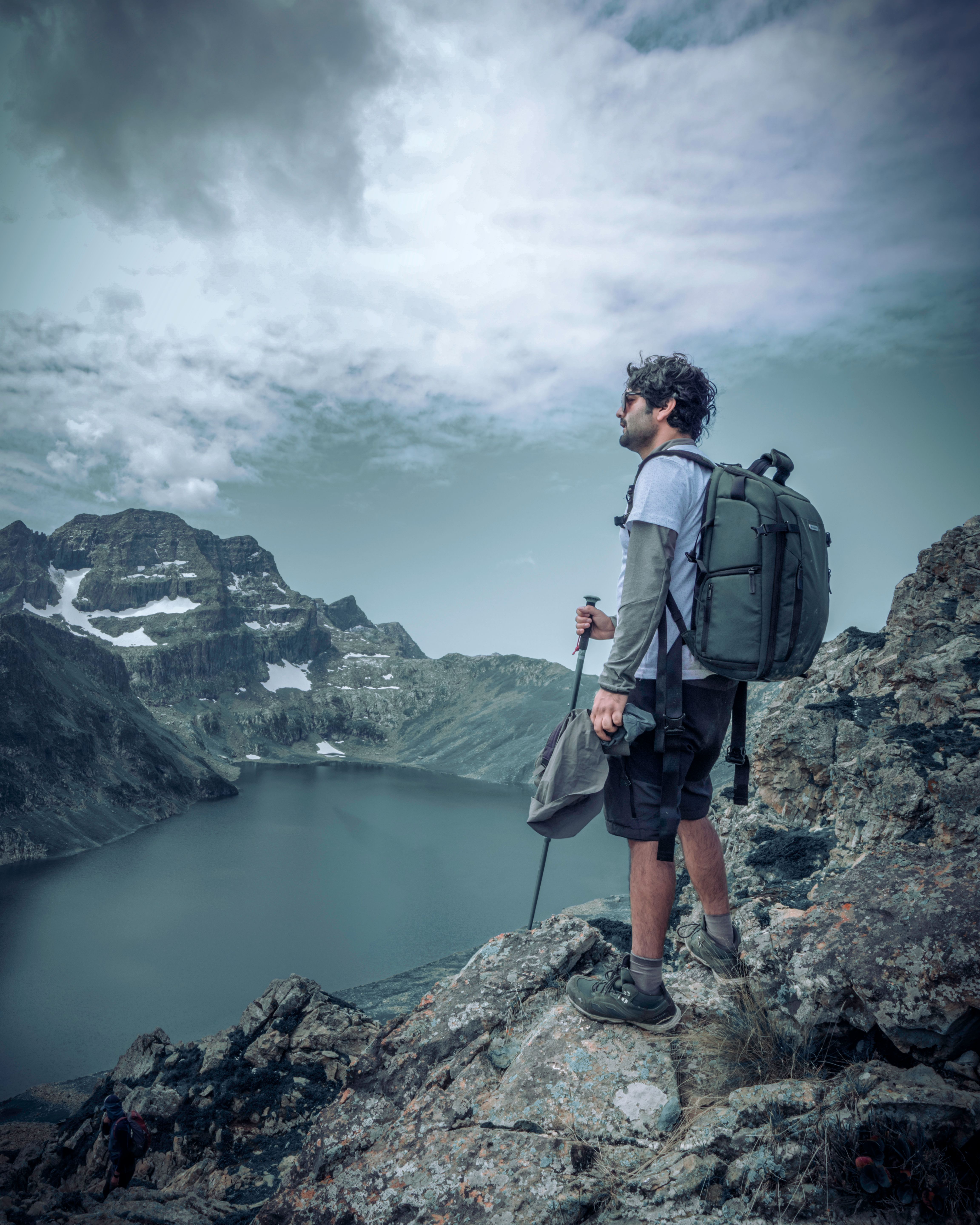 A Man Carrying Backpack Standing on the Rock · Free Stock Photo