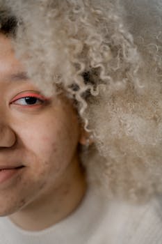 Detailed close-up of a woman's half face with distinctive curly hair and vibrant makeup.