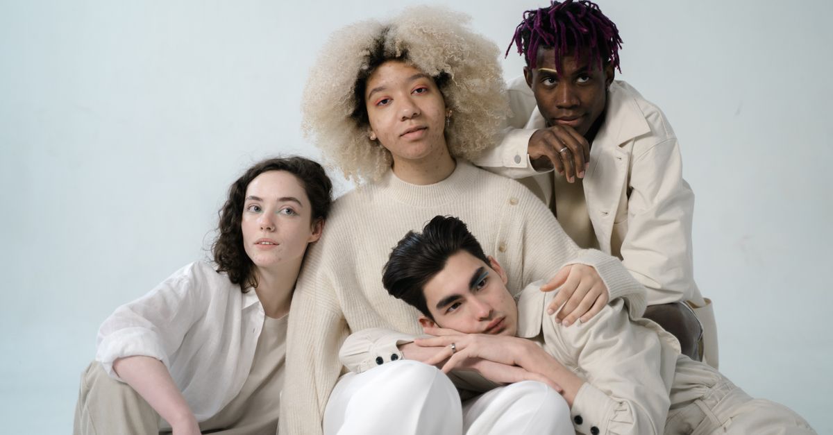 A diverse group of young adults posing together in a studio setting.