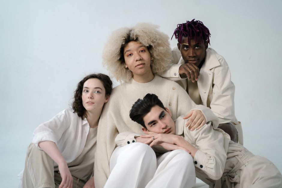 A diverse group of young adults posing together in a studio setting.